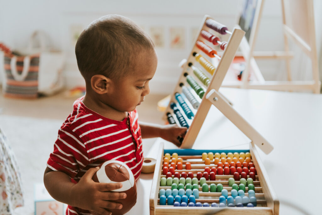 A child plays with a colorful wooden abacus toy