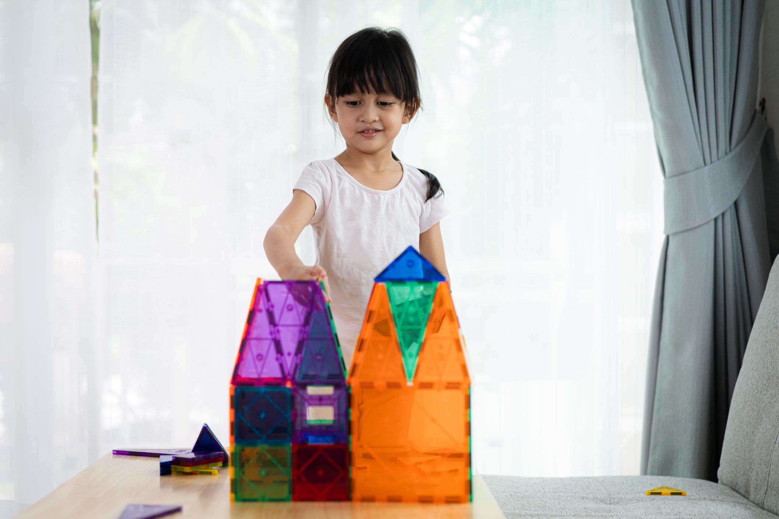Schoolkind bouwt geconcentreerd met magnetische bouwtegels - speelgoed schoolkind leren