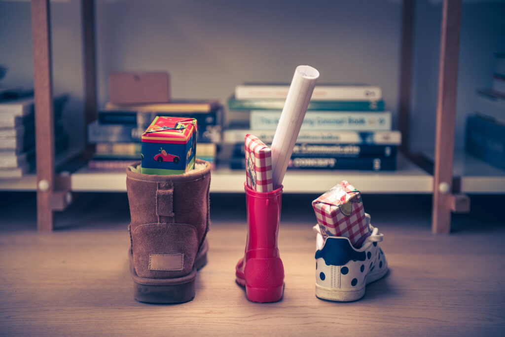 Three children's shoes with small gifts inside; placing shoes out for a sustainable St. Nicholas gift