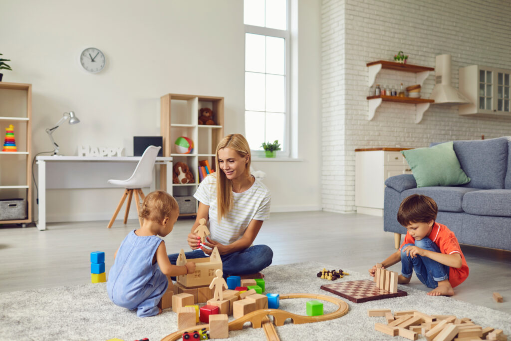 A mother and her two children are building with wooden blocks: sustainable toys that can be used by multiple children