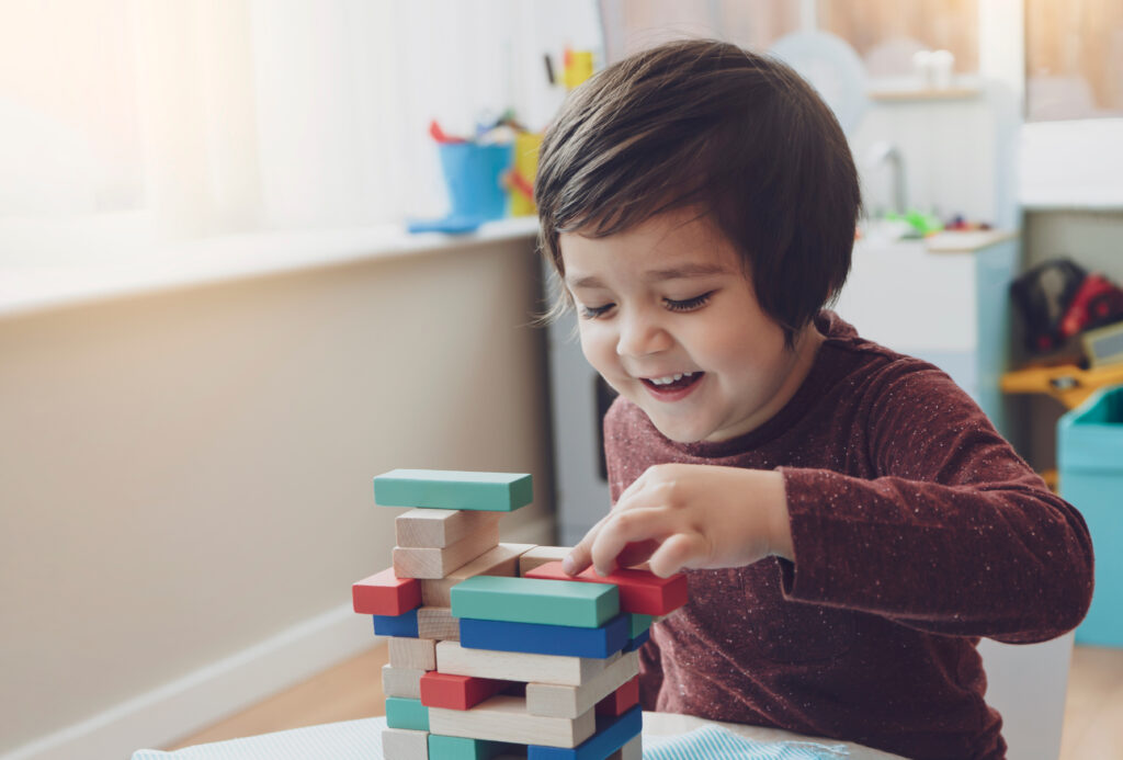 Kind bouwt geconcentreerd een balanstoren met houten plankjes